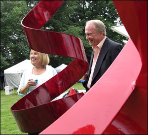 Sue and Larry Mullins are framed by a sculpture at the Crosby Festival preview party at Toledo Botanical Garden.