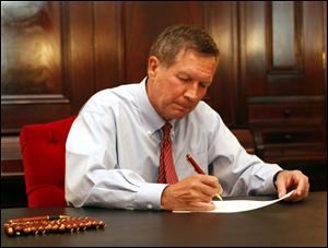 Gov. John Kasich signs the state budget bill in a brief ceremony. The two-year, $55.8 billion spending plan includes broad-reaching policy changes such as performance pay for teachers, expansion of school vouchers, and privatization of state assets.