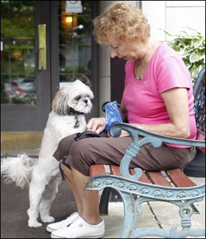 Sally Jeffrey, a professional pet sitter, lets Rascal, a female shih-tzu, have a treat after their walk around the perimeter of Sunset House.