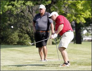 Dave Pifer, left, watches as Tim Toland, right, golfs during the Savage Foundation Golf Classic at the Belmont Country Club.
