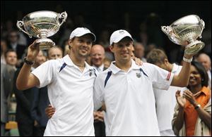 Mike Bryan of the United States, right, and doubles partner Bob Bryan of the United States hold aloft their trophies after winning the men's doubles final against Sweden's Robert Lindstedt and Romania's Horia Tecau at at Wimbledon.