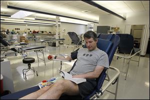 Robert Harden of Toledo, a dedicated donor, reads while donating blood at the American Red Cross blood center on Executive Parkway. The Western Lake Erie Blood Services Region for northwest Ohio and southeast Michigan is keeping its donation centers open  throughout the holiday weekend.