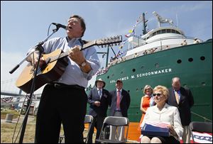  Russ Franzen sings during the rechristening of the SS Willis B. Boyer to SS Col. James M. Schoonmaker, at International Park in Toledo on Friday.  Watching from back left are, James M. Schoonmaker II,  Paul LaMarre, III, executive director of the Col. James M. Schoonmaker Museum Ship, Treecie Schoonmaker, wife, of James, U.S. Rep. Marcy Kaptur, seated, and Chris Gillcrist, executive director of the Great Lakes Historical Society.  