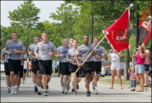SSG Dale Nelson, front,  holds the 983rd Engineer Battalion flag, which is in Monclova, Ohio, as members of his battalion run to the finish line together during the first annual Heroes Run through the streets of downtown Toledo on July 2, 2011.