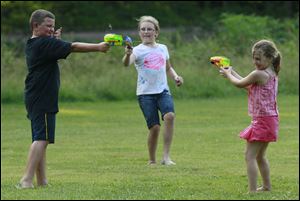 Brooklyn Tolson, 6, at right, and her sister Kaitlyn Toson, 10, battle their cousin, at left, Alex Walker, 9, with a squirt gun at Side Cut Metro park in Maumee.