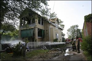 Toledo firefighters pour water on smoldering debris thrown from a house on fire on 943 Post St. Saturday.