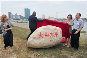 Mayor Mike Bell and Dashing Pacific's Wu King Hung unveil a symbolic rock as Toledo Zoo Director Ann Baker, left, and Dashing Pacific's Yuan Xiaohong watch. 