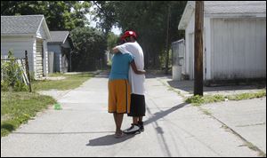 Iesha Collins, 17, who is the sister of slain teen Marquan McCuin, 18, hugs her cousin, who did not want to be identified, near the spot in the alley behind the 7-Eleven where the body was found.