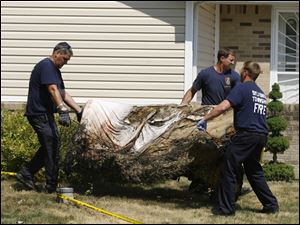 Sylvania Township Fire Department personnel carry away a damaged bed Monday at the scene of an Inland Drive fatal fire.