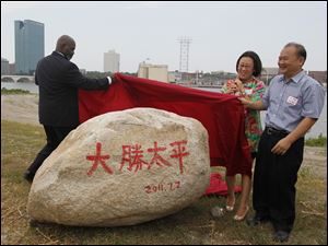 Toledo Mayor Mike Bell, Tina Yuan (Yaun Xiaohong) and Wu King Hung unveil a symbolic rock at the Marina District.