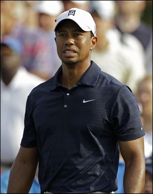 Tiger Woods grimaces after hitting a shot at The Players Championship, which he withdrew from after only nine holes.