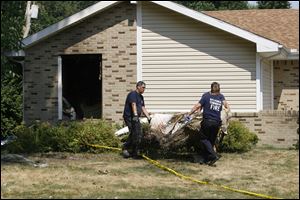 Sylvania Township Fire Department personnel clean up at the scene of the homicide and fire.