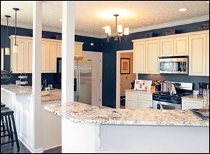 The kitchen’s antiqued white cabinets and dark walls make a perfect backdrop for the beautifully veined granite countertop.