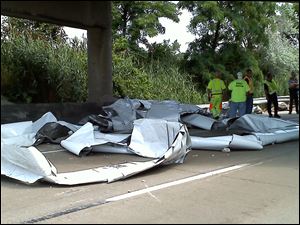 Road workers clean up unraveled spools of aluminum on the entrance ramp to I-280 from southbound I-75.