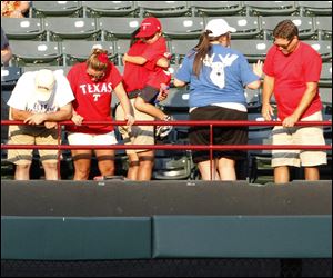 People look over the outfield railing after baseball fan Shannon Stone fell while trying to grab a ball in the second inning of Thursday's baseball game between the Texas Rangers and the Oakland Athletics in Arlington, Texas. Stone, who was at the game with his young son, caught the ball, tumbling over the outfield railing and falling about 20 feet onto concrete. He died shortly after at the hospital.
