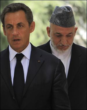 Afghan President Hamid Karzai right, walks along with French President Nicolas Sarkozy to address a news conference Tuesday at the presidental palace in Kabul, Afghanistan. Karzai says his half brother's assassination reflects the suffering of all Afghan people.