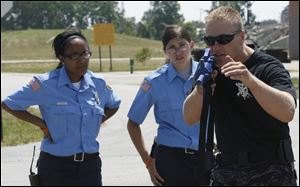 Justice Shannon, 15, left, and Sara Rufenacht, 14, of Wauseon Explorers  listen as Perrysburg Township police officer and Wood County Sheriff Special Response Team member Jim Ball reviews the correct way to carry a long gun.