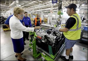 Congresswoman Marcy Kaptur watches as assembly team member Jim Chandler, right, loads a completed transmission into a shipping container during a visit to the GM Toledo Transmission Plant last summer.
