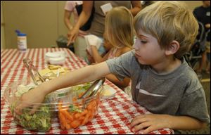 Following a tour of the new children's garden and story time, Braxon Lake, 5, takes advantages of vegetables that were reportedly caught while trying to escape in the Runaway Garden at the Bedford Branch Library. 