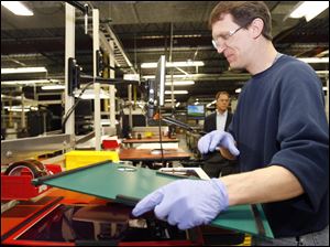Tim Zielinski, an employee of Xunlight Corporation, works on flexible solar panels while working out of their Toledo office in this December 2010 file photo.