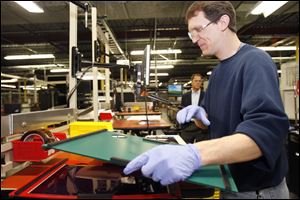 Tim Zielinski, an employee of Xunlight Corporation, works on flexible solar panels while working out of their Toledo office in this December 2010 file photo.