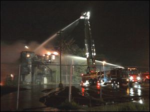 Firefighters spray the top of the building with hoses from the ground and aerial ladders. 