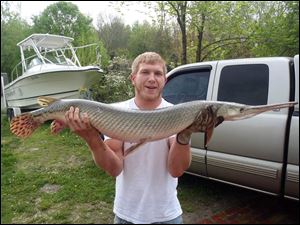 Zachary Jared proudly shows off his record 19.21-pound longnose gar he took May 12 at Turkeyfoot Lake in Summit County.