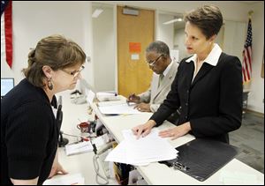 Michelle Wagner, right, and Judge C. Allen McConnell, center, who is seeking a third term, file petitions to run for openings on the Toledo Municipal Court bench. Lori Jacek of the elections board is at left. 
