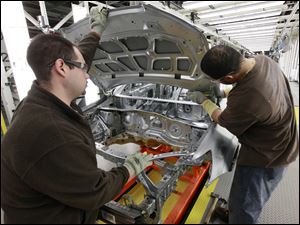 Assembly line workers Dave Zamora, left, and Steven Saleem work on a pre-production Chevrolet Sonic at the General Motors Orion Assembly plant in Orion Township, Mich.