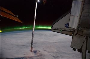 This panoramic view provided by NASA was photographed from the International Space Station,  looking past the docked space shuttle Atlantis' cargo bay and part of the station, including a solar array panel toward Earth, was taken on July 14, 2011, as the joint complex passed over the southern hemisphere. Aurora Australis, or the Southern Lights, can be seen on Earth's horizon and a number of stars are visible also. 