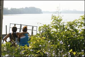 A pair of women watch as a lone Coast Guard boat searches for a missing man in the Maumee River off of Cullen Park Monday.
