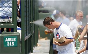 Ross Perry uses the mist-maker at Wrigley Park to cool off from the 95-degree heat before his favorite team, the Cubs, squares off  against the Marlins in Chicago.