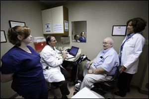 Dr. George Darah speaks with David Hensel, 79, as his granddaughter Shaintell Hensel, far left, and their 'care navigator,' Brenda Mullen, listen. The navigator concept is to guide patients through the health-care system.