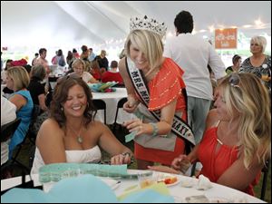 Mrs. Midwest Galaxy Katie Maskey, center, sells raffle tickets to Kim Fenneken, left, and Tiffany Holdgate during the Chicks for Charity mix at the Toledo Botanical Garden. The event raised funds for a boxing club.