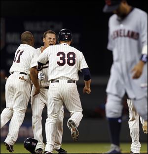 Minnesota Twins' Danny Valencia celebrates with teammates Ben Revere (11) and Luke Hughes (38) after hitting a two-run single to beat the Cleveland Indians 2-1 Tuesday in Minneapolis. At right is Indians' Orlando Cabrera. 