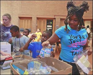Jazmyliena Martin, 14, packs a Manna Bag with nonperishable items at St. Paul’s United Methodist Church in Toledo. The bags are being given out to the needy in the Toledo area.