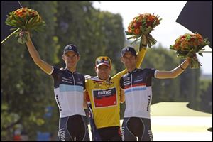 Cadel Evans of Australia, wearing the overall leader's yellow jersey, stands on the podium after winning the Tour de France cycling race in Paris, France, Sunday.  At left is 2nd placed Andy Schleck of Luxembourg and at right his brother Frank Schleck of Luxembourg who placed 3rd.