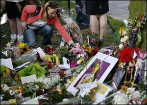 An unidentified woman leaves a floral tribute outside the home of singer Amy Winehouse in Camden Square, north London, Sunday. Amy Winehouse, the beehived soul-jazz diva whose self-destructive habits overshadowed a distinctive musical talent, was found dead Saturday.