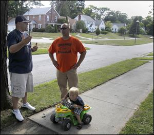 Oregon resident Scott Schultz, left, tells his neighbor Tom Lambrecht about the attempted abduction of his son, Tyler, 2, on tractor, in front of their Eastmoreland Drive home.