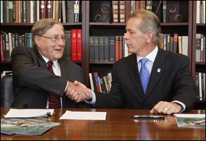 Dr. Lloyd Jacobs, president of the University of Toledo, left, shakes hands with Randy Oostra, president and chief executive officer of ProMedica after signing an alliance that includes a new scholarship. 