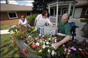 Gloria Steger, left, Linda McCord, and Donnie Dixon pluck dead  flowers as they work in the garden at Whitehouse Country Manor.