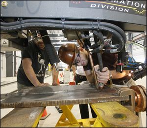 Welder Jason Parkhurst, left, and welding engineer Jared Nevel, both of Monroe, set up a machine at the new headquarters for Ventower Industries LLC in Monroe. The firm has hired 20 employees so far.