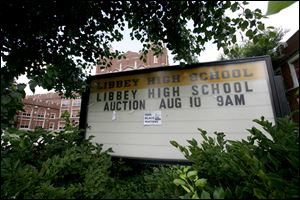 The sign announcing the auction is overgrown with weeds. An auction of the school’s contents was held this spring. Buyers stripped lockers from interior walls, dismantled cabinets, and searched rooms of the building for valuables.