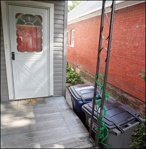 The Decosters put the two city-issued receptacles against the porch of their East Toledo home, with the wheels toward the curb, to make taking out the trash easier. The city has no requirements on can placement.