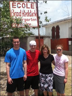 Debbie Reddick, second from right, a Perrysburg Schools employee, joined John, Jim, and Grace, the three youngest of her eight children, recently outside the K-6 school in Savanette, Haiti, that is named for Ms. Reddick's late husband.