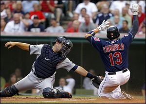 Cleveland Indians' Asdrubal Cabrera slides safely into home ahead of the tag by Detroit Tigers catcher Alex Avila on a sacrifice fly by teammate Carlos Santana Tuesday  night.