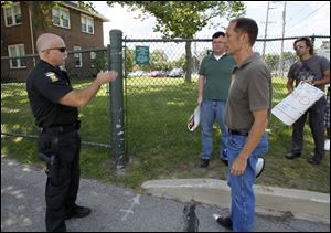 Toledo Police Lt. Norman Giesige, left, tells protesters  Grant Williams of Columbus, front, Greg Lyons of Toledo, back, and Eric Marks of Toledo, right, that they cannot go on Inverness Club property. They called on U.S. House Speaker John Boehner to create jobs in Ohio. 