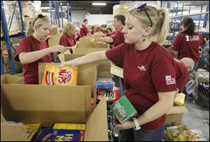 Hickory Farms employees Lisa Gardner, left, and Angie Noorman, right, pack food boxes at the Toledo Northwestern Ohio Food Bank in Toledo, Wednesday, August 10, 2011.