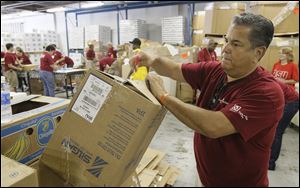 Hickory Farms CEO Mark Rodriguez breaks down a box as other Hickory Farms employees pack food boxes at the Toledo Northwestern Ohio Food Bank in Toledo, Wednesday, August 10, 2011.