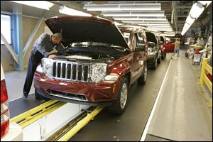 An inspector examines the engine of Jeep Liberty as it goes through the certification line.